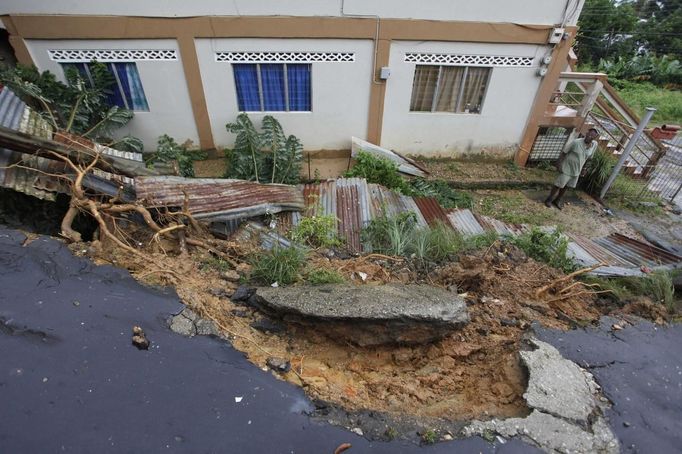 Pensioner Theophile Jpseh looks at the broken fence and damaged road outside his home at Upper Mount Pleasant Road, Carenage, about 8 km (5 miles) west of the capital Port of Spain, which was caused by the passing of Tropical Storm Isaac August 23, 2012. Tropical Storm Isaac unleashed heavy rain and winds off Puerto Rico and the Virgin Islands as it moved across the Caribbean on Thursday and could strengthen into a hurricane before tearing across the Dominican Republic and Haiti. REUTERS/Andrea De Silva (TRINIDAD AND TOBAGO - Tags: DISASTER ENVIRONMENT) Published: Srp. 24, 2012, 2 dop.