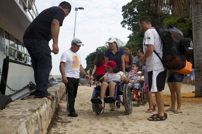 Marcilene Castro (3rd L) takes her daughter Alice, 17, who suffers from mild cerebral palsy, to board a boat in order to attend a "Bototherapy" session at Arau River in Amazon August 11, 2012. The "Bototherapy", a "Rolfing" therapeutic practice assisted by river dolphins, was developed by Igor Andrade, a physiotherapist, and the treatment is free for children with disabilities or disorders from low income families. Picture taken August 11, 2012. REUTERS/Bruno Kelly (BRAZIL - Tags: SOCIETY HEALTH) Published: Srp. 28, 2012, 1:55 dop.