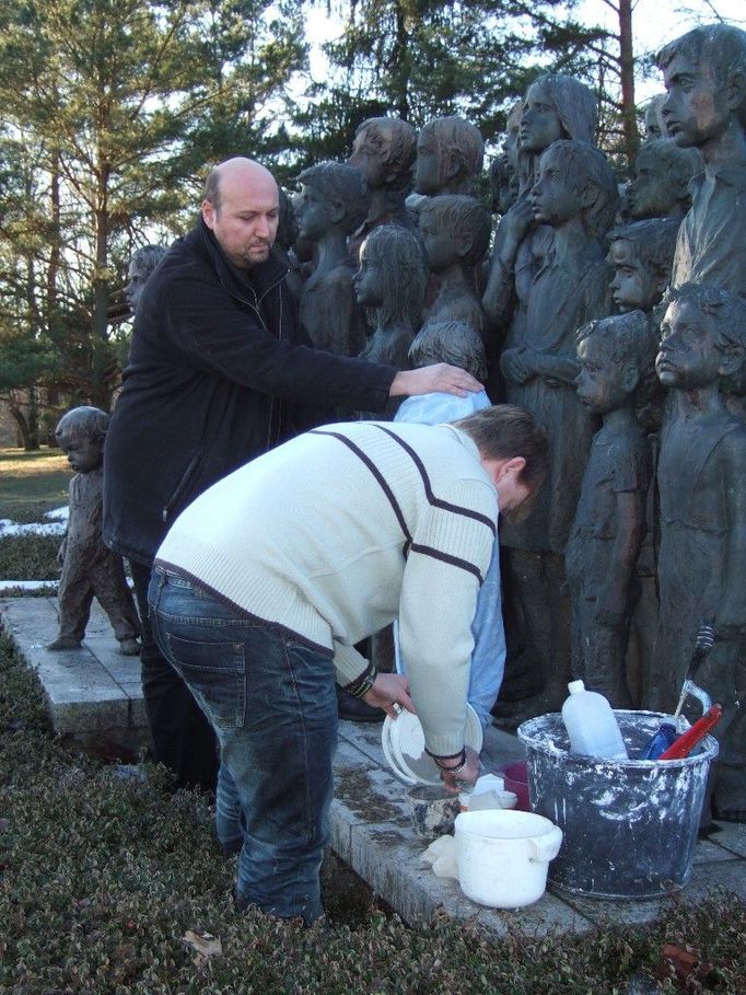 Spolupracovníci restaurátora Oldřicha Hejtmánka umisťují znovuodlitou sochu děvčátka do sousoší v Lidicích.