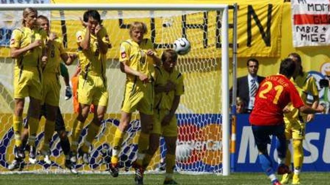 Španělský útočník David Villa (v červeném) střílí volný přímý kop, který po teči ukrajinské zdi skončil gólem. V zápase skupiny H vedlo Španělsko nad Ukrajinou 2:0.