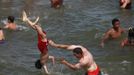 People play in the water at the beach at Coney Island in the Brooklyn borough of New York June 30, 2012. About 3.9 million homes and businesses were without power on Saturday amid a record heat wave in the eastern United States after deadly thunderstorms downed power lines from Indiana to New Jersey. REUTERS/Eric Thayer (UNITED STATES - Tags: ENVIRONMENT SOCIETY) Published: Čer. 30, 2012, 8:36 odp.