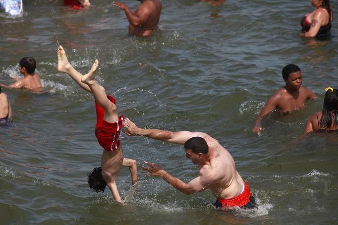 People play in the water at the beach at Coney Island in the Brooklyn borough of New York June 30, 2012. About 3.9 million homes and businesses were without power on Saturday amid a record heat wave in the eastern United States after deadly thunderstorms downed power lines from Indiana to New Jersey. REUTERS/Eric Thayer (UNITED STATES - Tags: ENVIRONMENT SOCIETY) Published: Čer. 30, 2012, 8:36 odp.