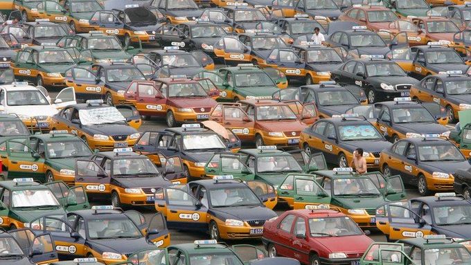 Taxíkáři čekají na zákazníky na novém letišti v Pekingu. Šedesát šest tisíc jejich řidičů prošlo v rámci zlepšení obrazu města před olympiádou kurzem angličtiny, hygienických návyků a chování.