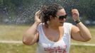 Sophie Riviere refreshes herself at a sprinkler as she walks in the National Mall in Washington June 21, 2012. A heat wave blanketed the U.S. Mid-Atlantic and Northeast on Thursday, forcing utilities across the region to ask customers to conserve electricity. REUTERS/Jose Luis Magana (UNITED STATES - Tags: ENERGY ENVIRONMENT SOCIETY) Published: Čer. 21, 2012, 5:50 odp.