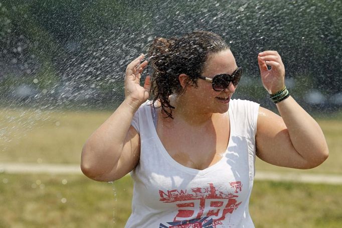 Sophie Riviere refreshes herself at a sprinkler as she walks in the National Mall in Washington June 21, 2012. A heat wave blanketed the U.S. Mid-Atlantic and Northeast on Thursday, forcing utilities across the region to ask customers to conserve electricity. REUTERS/Jose Luis Magana (UNITED STATES - Tags: ENERGY ENVIRONMENT SOCIETY) Published: Čer. 21, 2012, 5:50 odp.