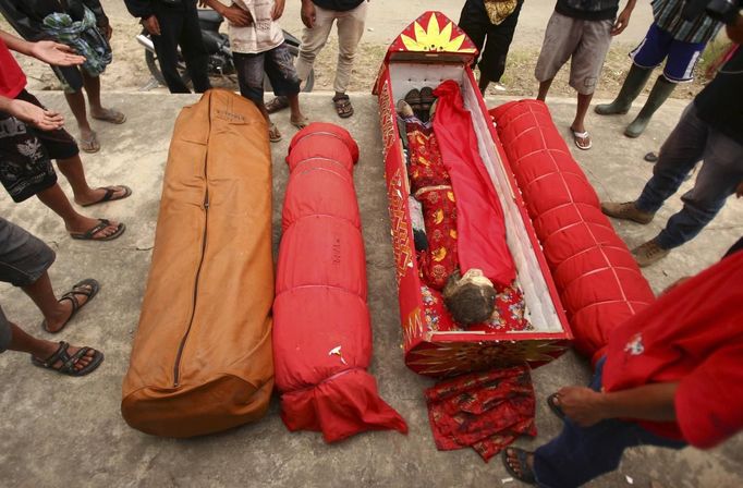 A mummy lies in a coffin beside other bodies in front of a grave house called Patane after being given new clothes in a ritual in the Toraja district of Indonesia's South Sulawesi Province, August 23, 2012. The ritual, called Ma'nene, involves changing the clothes every three years of mummified ancestors to honor love for the deceased. Locals believe dead family members are still with them, even if they died hundreds of years ago, a family spokesman said. Picture taken August 23, 2012. REUTERS/Yusuf Ahmad (INDONESIA - Tags: SOCIETY RELIGION) Published: Srp. 24, 2012, 1:13 odp.