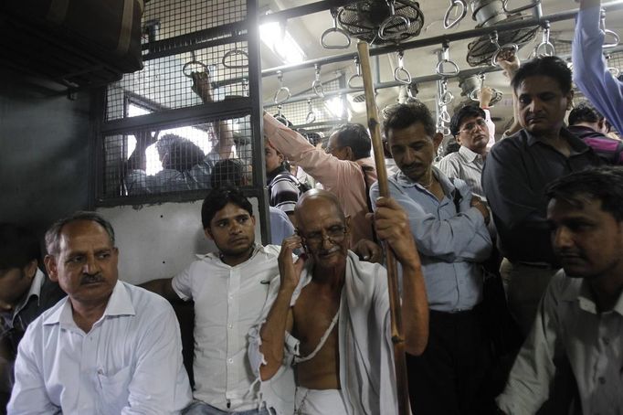 Mahesh Chaturvedi (front C), 63, who dresses up like Mahatma Gandhi, talks on the phone in the outskirts of New Delhi September 28, 2012. Chaturvedi says that the soul of Gandhi resides in him and he has been sent to continue the work of Father of the Nation. After his self proclaimed transformation in 2002 as Gandhi, Chaturvedi has been travelling extensively and plays up to his startling resemblance to Gandhi at protests and demonstrations. Picture taken September 28, 2012. REUTERS/Mansi Thapliyal (INDIA - Tags: SOCIETY) Published: Lis. 26, 2012, 3:55 dop.