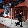 Mariachi musician walks past a mural in the Boyle Heights area of Los Angeles, home to many Mexican migrants, in California