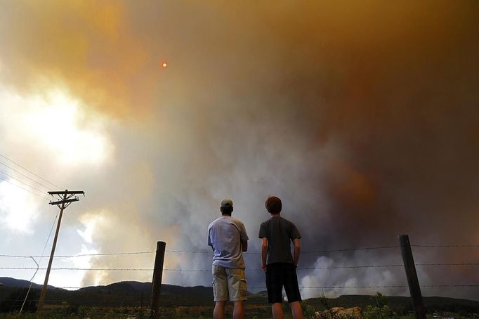 Robby Wood (L) of Denver, Colorado and his 16-year-old nephew Jacob Wood also of Denver, Colorado watch as smoke and flames encroach upon homes and ranches on the eastern front of the High Park Fire near Laporte, Colorado June 10, 2012. The fire started on Saturday and was estimated at more than 14,000 acres on Sunday morning. At least 18 structures were lost or damaged due to the fire with more threatened and officials are searching for one person believed to be missing. The cause of the fire is unknown and it remains at zero percent containment. REUTERS/Marc Piscotty (UNITED STATES - Tags: DISASTER ENVIRONMENT SOCIETY) Published: Čer. 11, 2012, 12:07 dop.