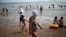 A woman, wearing a nylon mask, walks on the shore during her visit to a beach in Qingdao, Shandong province July 6, 2012. The mask, which was invented by a woman about seven years ago, is used to block the sun's rays. The mask is under mass production and is on sale at local swimwear stores. REUTERS/Aly Song (CHINA - Tags: SOCIETY TRAVEL ENVIRONMENT) TEMPLATE OUT Published: Čec. 6, 2012, 4:33 odp.