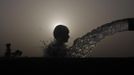 A boy is silhouetted against the setting sun as he cools himself off under a pipe during a hot day in Faisalabad on June 27, 2012. Temperatures reached 40 degrees Celcius (104 degrees Fahrenheit) in Faisalabad and the weather remained hot in some other parts of the country, the Pakistan Meteorological Department said on their website. REUTERS/Fayyaz Hussain (PAKISTAN - Tags: SOCIETY ENVIRONMENT) Published: Čer. 27, 2012, 3:55 odp.