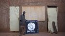 Hotel worker Abderrahmane Toure poses for a picture next to a sign for radical Islamist group Movement for Unity and Jihad in West Africa (MUJAO) in Douentza January 28, 2013. The sign reads, "There is no God but Allah and Mohammad is his prophet." REUTERS/Joe Penney (MALI - Tags: RELIGION CIVIL UNREST POLITICS CONFLICT) Published: Led. 28, 2013, 8:32 odp.