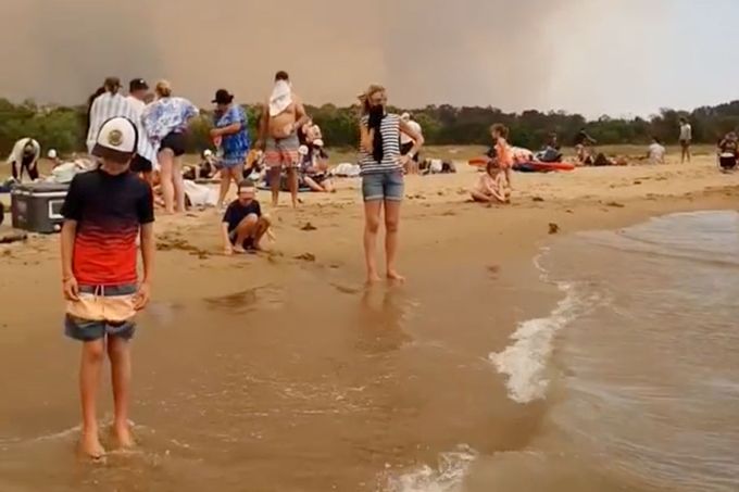 Lidé na pláži v Austrálii během požárů.
