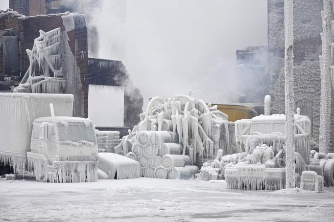 Ice-covered trucks are blanketed in smoke after a warehouse fire in Chicago January 23, 2013. Fire department officials said it is the biggest fire the department has had to battle in years and one-third of all Chicago firefighters were on the scene at one point or another trying to put out the flames. An Arctic blast continues to grip the U.S. Midwest and Northeast Wednesday, with at least three deaths linked to the frigid weather, and fierce winds made some locations feel as cold as 50 degrees below zero Fahrenheit. (minus 46 degrees Celsius). REUTERS/John Gress (UNITED STATES - Tags: DISASTER ENVIRONMENT) Published: Led. 23, 2013, 5:54 odp.