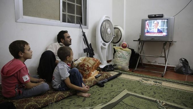 Bojovník z řad povstalců sleduje doma s rodinou Obamův projev.