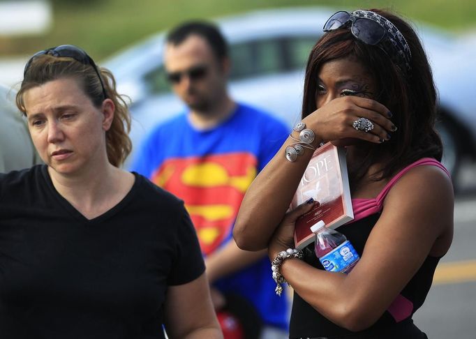 Naomi Hicks (L) and Faith Goins attend a memorial for victims, behind the theater where a gunman opened fire on moviegoers in Aurora, Colorado July 21, 2012. James Holmes, the suspect accused of a shooting rampage at a Denver-area premiere of the new "Batman" film, received a high volume of deliveries at work and home over the past four months, police said, parcels they believe contained ammunition and possibly bomb-making materials. REUTERS/Shannon Stapleton (UNITED STATES - Tags: CRIME LAW CIVIL UNREST SOCIETY OBITUARY) Published: Čec. 22, 2012, 12:16 dop.