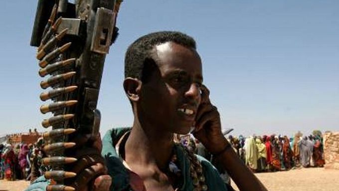 Jeden ze somálských ozbrojenců "hlídkuje" u fronty lidí, čekajících na potravinovou pomoc.