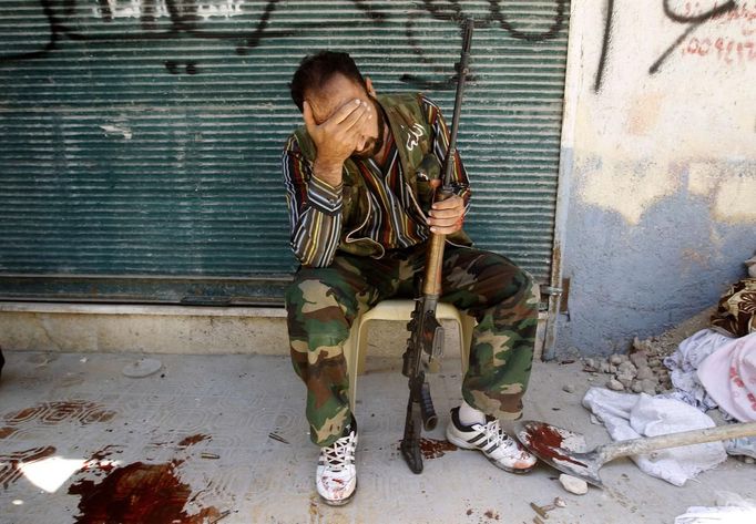 RNPS IMAGES OF THE YEAR 2012 - A Free Syrian Army fighter reacts after his friend was shot by Syrian Army soldiers during clashes in the Salah al-Din neighbourhood in central Aleppo August 4, 2012. The rebel's friend was killed from a very accurate Syrian army sniper who found a hole in between sandbags and fired. The sniper shot him in the chest. I just ran fast across the street and took the pictures in really bad light - strong highlights and dark shadows. This rebel was definitely close to the fighter who'd been shot. He was in bad shape and crying a lot. REUTERS/Goran Tomasevic (SYRIA - Tags: CIVIL UNREST MILITARY POLITICS) Published: Pro. 4, 2012, 1:19 dop.