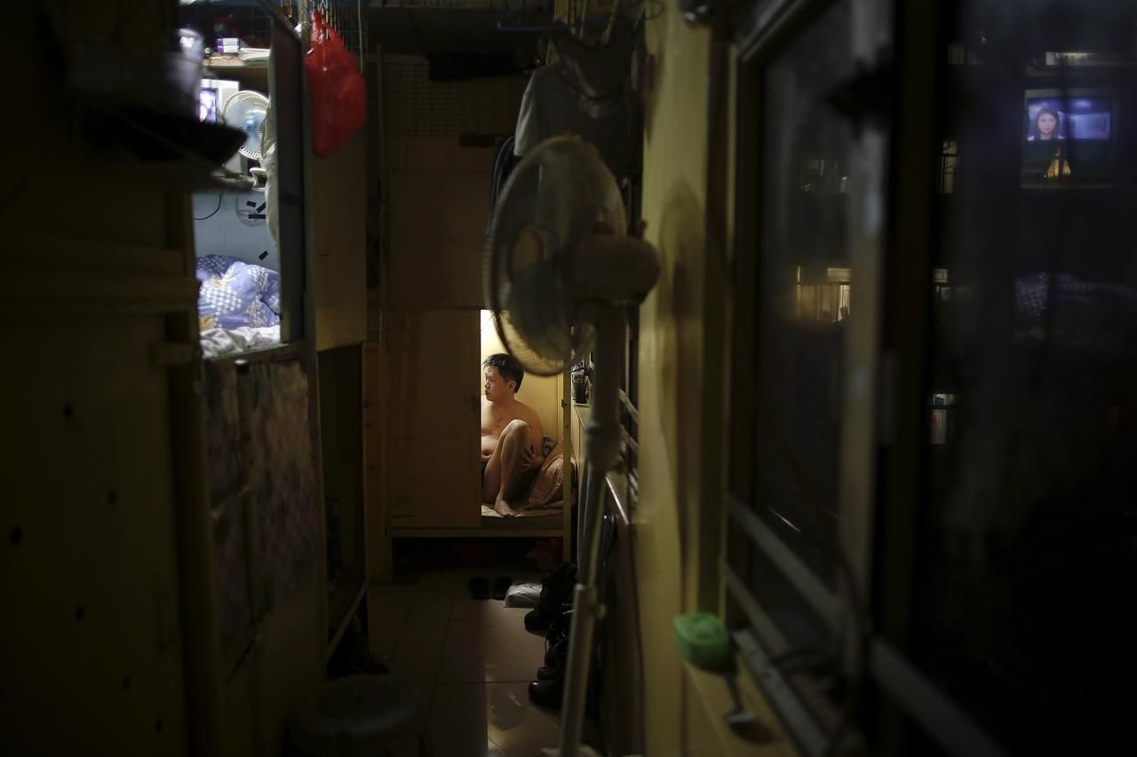 Akee, 34, who works as a waiter rests in a wooden box that he lives in Hong Kong October 9, 2012. In Hong Kong's middle-class residential area, short distance from its shopping and financial districts, 24 people live in these wooden boxes, or "coffin homes", packed in a single apartment of little over 50 square meters. Its residents pay 1450 Hong Kong dollars ($180) for their living space built of wooden panels of 2 meters by 70 cm. To maximize income from the rent in central Hong Kong landlords build "coffin homes", nicknamed due to their resemblance to real coffins. Space has always been at a premium in Hong Kong where developers plant high-rises on every available inch. REUTERS/Damir Sagolj (CHINA - Tags: SOCIETY REAL ESTATE BUSINESS) Published: Říj. 9, 2012, 1:42 odp.