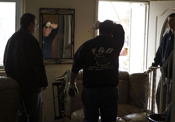 A family friend wipes his brow as he helps a family clean the flood damage debris out of their home in the New Dorp Beach neighborhood of the Staten Island borough of New York, November 1, 2012. Deaths in the United States and Canada from Sandy, the massive storm that hit the U.S. East Coast this week, rose to at least 95 on Thursday after the number of victims reported by authorities in New York City jumped and deaths in New Jersey and elsewhere also rose. REUTERS/Lucas Jackson (UNITED STATES - Tags: ENVIRONMENT DISASTER) Published: Lis. 1, 2012, 10:22 odp.