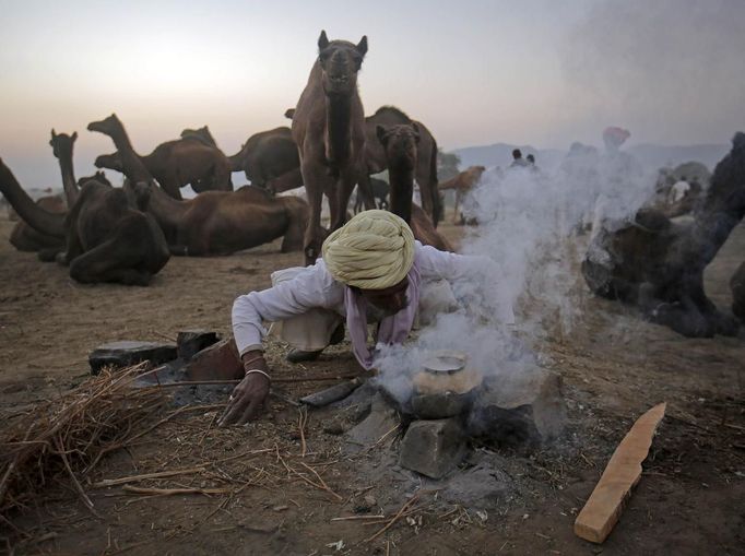 A camel herder lights a fire to cook on at Pushkar Fair in the desert Indian state of Rajasthan November 23, 2012. Many international and domestic tourists throng to Pushkar to witness one of the most colourful and popular fairs in India. Thousands of animals, mainly camels, are brought to the fair to be sold and traded. REUTERS/Danish Siddiqui (INDIA - Tags: SOCIETY ANIMALS) Published: Lis. 23, 2012, 5:38 odp.