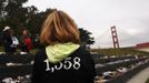 A woman wears a t-shirt bearing the number of people who have jumped to their death from the Golden Gate Bridge, while people look at shoes worn by those who have perished from the bridge, in San Francisco, California May 27, 2012. The iconic bridge is celebrating its 75th anniversary with a series of events. REUTERS/Robert Galbraith (UNITED STATES - Tags: SOCIETY ENVIRONMENT) Published: Kvě. 27, 2012, 8:26 odp.