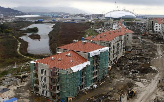 A general view shows the construction site of the Olympic athletes village in front of the Olympic Park with the Olympic stadium for the Sochi 2014 Winter Olympics in Adler, near Sochi February 18, 2013. Although many complexes and venues in the Black Sea resort of Sochi mostly resemble building sites that are still under construction, there is nothing to suggest any concern over readiness. Construction will be completed by August 2013 according to organizers. The Sochi 2014 Winter Olympics opens on February 7, 2014. REUTERS/Kai Pfaffenbach (RUSSIA - Tags: BUSINESS CONSTRUCTION ENVIRONMENT SPORT OLYMPICS) Published: Úno. 18, 2013, 6:37 odp.