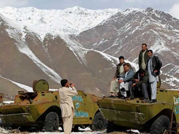 Afghánci v Pandžšírském údolí pózují na troskách sovětských armádních vozidel. Snímek z roku 2014.