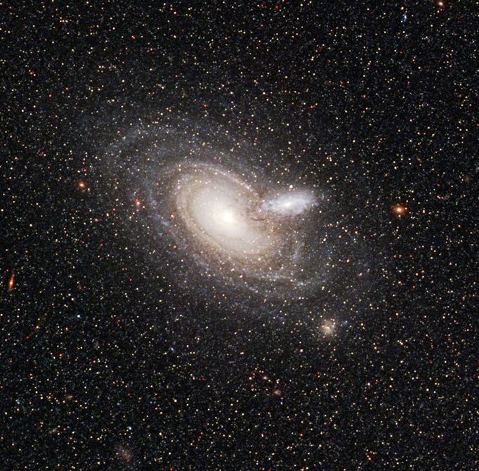 Release No.: STScI-2008-33 Credit: NASA, ESA, and The Hubble Heritage Team (STScI/AURA) Acknowledgement: B. Holwerda (Space Telescope Science Institute) and J. Dalcanton (University of Washington) NASA's Hubble Space Telescope has captured a rare alignment between two spiral galaxies. The outer rim of a small, foreground galaxy is silhouetted in front of a larger background galaxy. Skeletal tentacles of dust can be seen extending beyond the small galaxy's disk of starlight. Such outer dark dusty structures, which appear to be devoid of stars, like barren branches, are rarely so visible in a galaxy because there is usually nothing behind them to illuminate them. Astronomers have never seen dust this far beyond the visible edge of a galaxy. They do not know if these dusty structures are common features in galaxies. Understanding a galaxy's color and how dust affects and dims that color are crucial to measuring a galaxy's true brightness. By knowing the true brightness, astronomers can calculate the galaxy's distance from Earth. Astronomers calculated that the background galaxy is 780 million light-years away. They have not as yet calculated the distance between the two galaxies, although they think the two are relatively close, but not close enough to interact. The background galaxy is about the size of the Milky Way Galaxy and is about 10 times larger than the foreground galaxy. Most of the stars speckled across this image belong to the nearby spiral galaxy NGC 253, which is out of view to the right. Astronomers used Hubble's Advanced Camera for Surveys to snap images of NGC 253 when they spied the two galaxies in the background. From ground-based telescopes, the two galaxies look like a single blob. But the Advanced Camera's sharp "eye" distinguished the blob as two galaxies, cataloged as 2MASX J00482185-2507365. The images were taken on Sept. 19, 2006. The results have been submitted for publication in The Astronomical Journal.