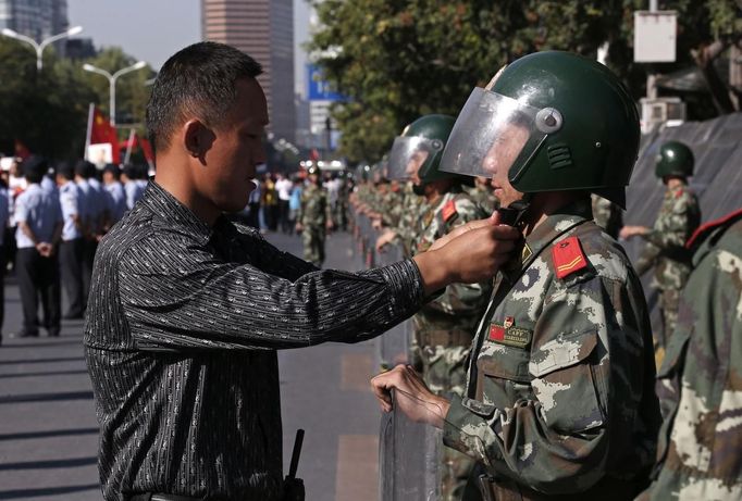 A plainclothes policeman helps a paramilitary policeman adjusts his helmet during an anti-Japan protest outside the Japanese embassy in Beijing on the 81st anniversary of Japan's invasion of China, September 18, 2012. Hundreds of Japanese businesses and the country's embassy suspended services in China on Tuesday, expecting further escalation in violent protests over a territorial dispute between Asia's two biggest economies. REUTERS/David Gray (CHINA - Tags: POLITICS CIVIL UNREST)