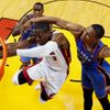 Basketbalista Dwayne Wade z Miami se snaží zavěsit přes bránící Russella Westbrooka (vpravo) a Kendricka Perkinse z Oklahomy ve finále play-off NBA 2012.