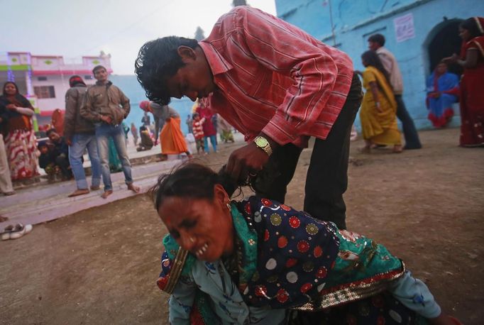 A man pulls a devotee, believed to be possessed by evil spirits, by the hair as she goes into a state of trance at Guru Deoji Maharaj temple during a ghost fair at Malajpur village in Betul district in the central Indian state of Madhya Pradesh January 27, 2013. People from across India come to this fair to be exorcised of �evil spirits�. They are usually brought by relatives and they are most often women. The exorcism involves running around the temple courtyard to make the 'ghost' weak then being beaten by a priest with a broom. Picture taken January 27, 2013. REUTERS/Danish Siddiqui (INDIA - Tags: SOCIETY RELIGION) ATTENTION EDITORS: PICTURE 4 OF 24 FOR PACKAGE 'INDIAN GHOSTBUSTERS' SEARCH 'INDIA GHOST' FOR ALL IMAGES Published: Úno. 5, 2013, 5:09 dop.