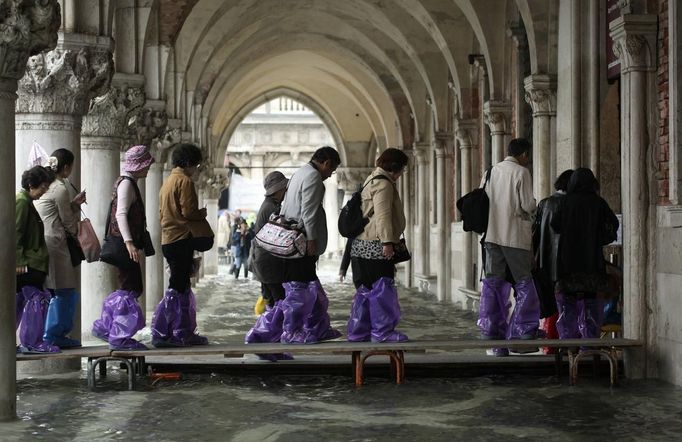 Tourists walk on raised platforms for flood waters in St. Mark Square during a period of seasonal high water in Venice October 27, 2012. The water level in the canal city rose to 127 cm (50 inches) above the normal level, according to the monitoring institute. REUTERS/Manuel Silvestri (ITALY - Tags: ENVIRONMENT SOCIETY TRAVEL) Published: Říj. 27, 2012, 12:05 odp.