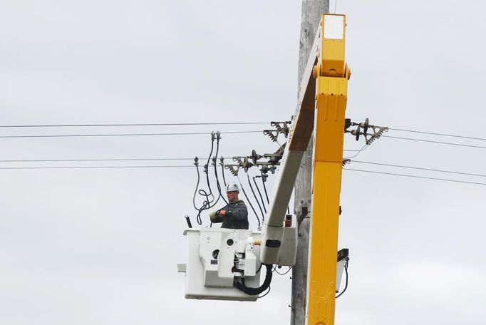 A power company worker in a cherry picker connects wires to a power line while working to restore electricity in East Massapequa, New York October 31, 2012. The U.S. Northeast began crawling back to normal on Wednesday after monster storm Sandy crippled transportation, knocked out power for millions and killed at least 45 people in nine states with a massive storm surge and rain that caused epic flooding. REUTERS/Lucas Jackson (UNITED STATES - Tags: ENVIRONMENT DISASTER) Published: Říj. 31, 2012, 2:05 odp.