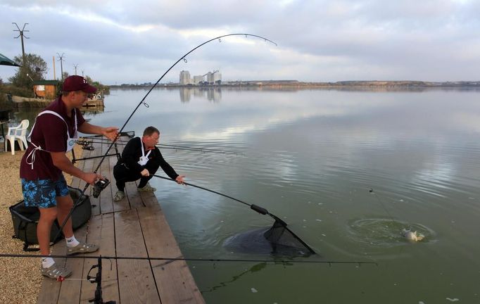 Krisztian Peter (L) and Norbert Barati (C) of Hungary catch a carp during the 14th Carpfishing World Championship in Corbu village, 310 km (192 miles) east of Bucharest, September 29, 2012. REUTERS/Radu Sigheti (ROMANIA - Tags: SOCIETY) Published: Zář. 29, 2012, 4:27 odp.