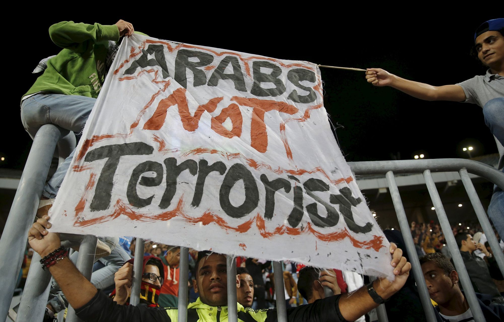 Egyptský fan oušek drží transparent "Arabové nejsou teroristé" před zápase kvalifikace MS 2018 s Čadem.