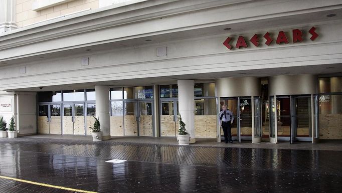 A security guard stands outside the entrance of Caesar's Casino on the Atlantic City boardwalk, with doors covered with sheets of plywood for protection from Hurricane Sandy as it approaches, October 28, 2012. East Coast residents scrambled on Sunday to prepare for Hurricane Sandy, which could make landfall as the largest storm to hit the United States, bringing battering winds, flooding and even heavy snow. REUTERS/Tom Mihalek (UNITED STATES - Tags: ENVIRONMENT)