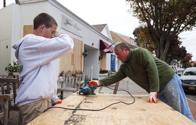 A father and son work to cut plywood sheets in preparation for the arrival of Hurricane Sandy in Westhampton Beach, New York, October 28, 2012. Hurricane Sandy could be the biggest storm to hit the United States mainland when it comes ashore on Monday night, bringing strong winds and dangerous flooding to the East Coast from the mid-Atlantic states to New England, forecasters said on Sunday. REUTERS/Lucas Jackson (UNITED STATES - Tags: ENVIRONMENT DISASTER)