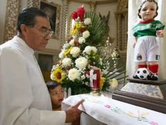 Kněz Jose Guadalupe Hernandez Sanchez v Pueblu stojí před oltář, na němž je Jezulátko v podobě malého fotbalisty v mexickém dresu.