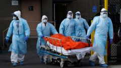Zdravotníci odvážejí ostatky jedné z obětí koronaviru z nemocnice Wyckoff Heights v New Yorku.
