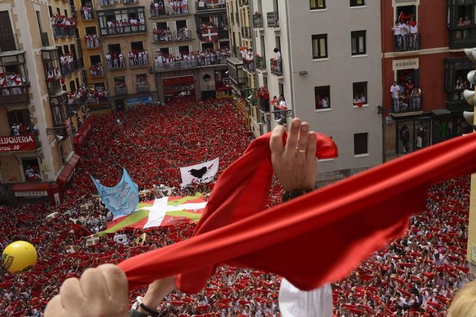 Revellers on the town hall balcony hold up red scarves during the start of the San Fermin Festival in Pamplona July 6, 2012. The festival, best known for its daily running of the bulls, kicked off on Tuesday with the traditional "Chupinazo" rocket launch and will run until July 14. REUTERS/Vincent West (SPAIN - Tags: SOCIETY) Published: Čec. 6, 2012, 11:53 dop.