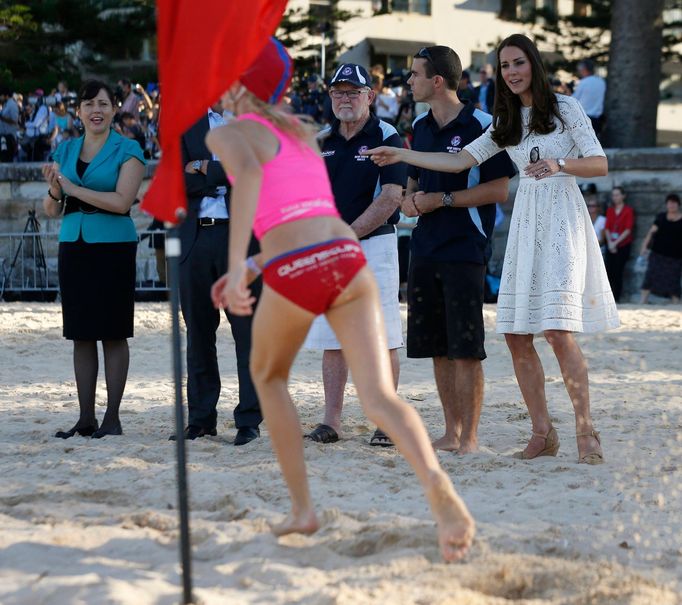 Catherine, Britain's Duchess of Cambridge, directs a young surf lifesaver to the finish line during a contest at a surf lifesaving demonstration at Sydney's Manly beach