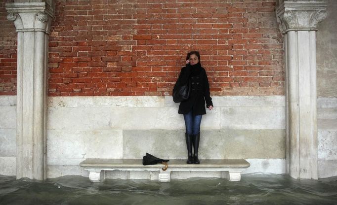 A woman stands on a bench above a flooded street during a period of seasonal high water in Venice November 11, 2012. The water level in the canal city rose to 149 cm (59 inches) above normal, according to the monitoring institute. REUTERS/Manuel Silvestri (ITALY - Tags: ENVIRONMENT SOCIETY) Published: Lis. 11, 2012, 2:22 odp.