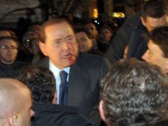 Zraněný Silvio Berlusconi opouští mítink své strany.