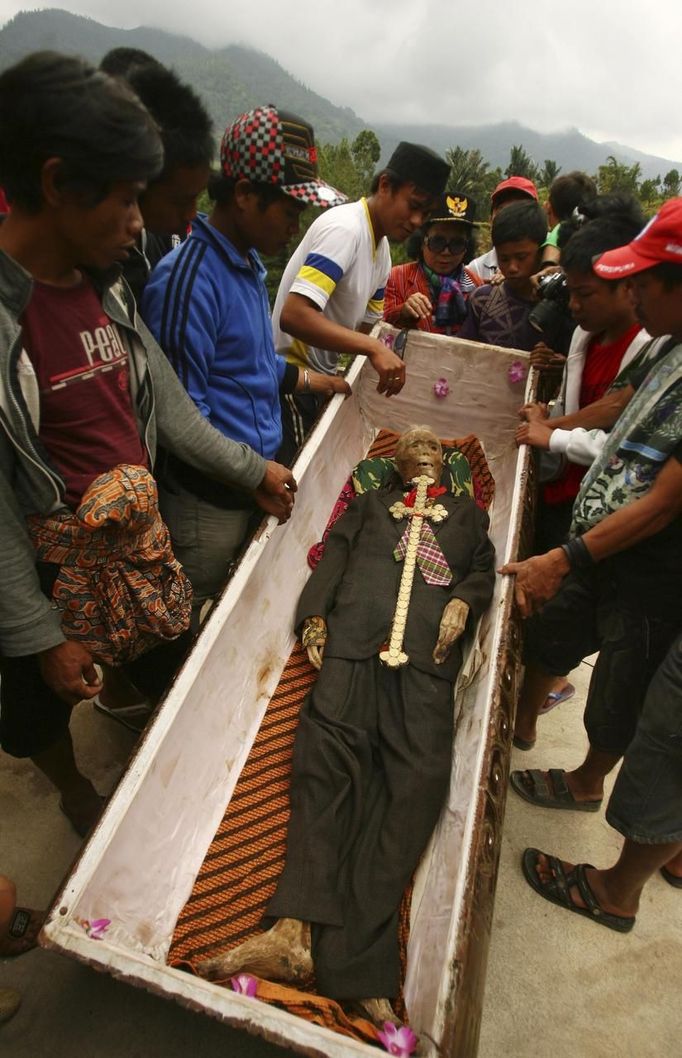 Family members surround a mummy before giving it new clothes in a ritual in the Toraja district of Indonesia's South Sulawesi Province, August 23, 2012. The ritual, called Ma'nene, involves changing the clothes of mummified ancestors every three years to honor love for the deceased. Locals believe dead family members are still with them, even if they died hundreds of years ago, a family spokesman said. Picture taken August 23, 2012. REUTERS/Yusuf Ahmad (INDONESIA - Tags: SOCIETY RELIGION) Published: Srp. 24, 2012, 12:52 odp.