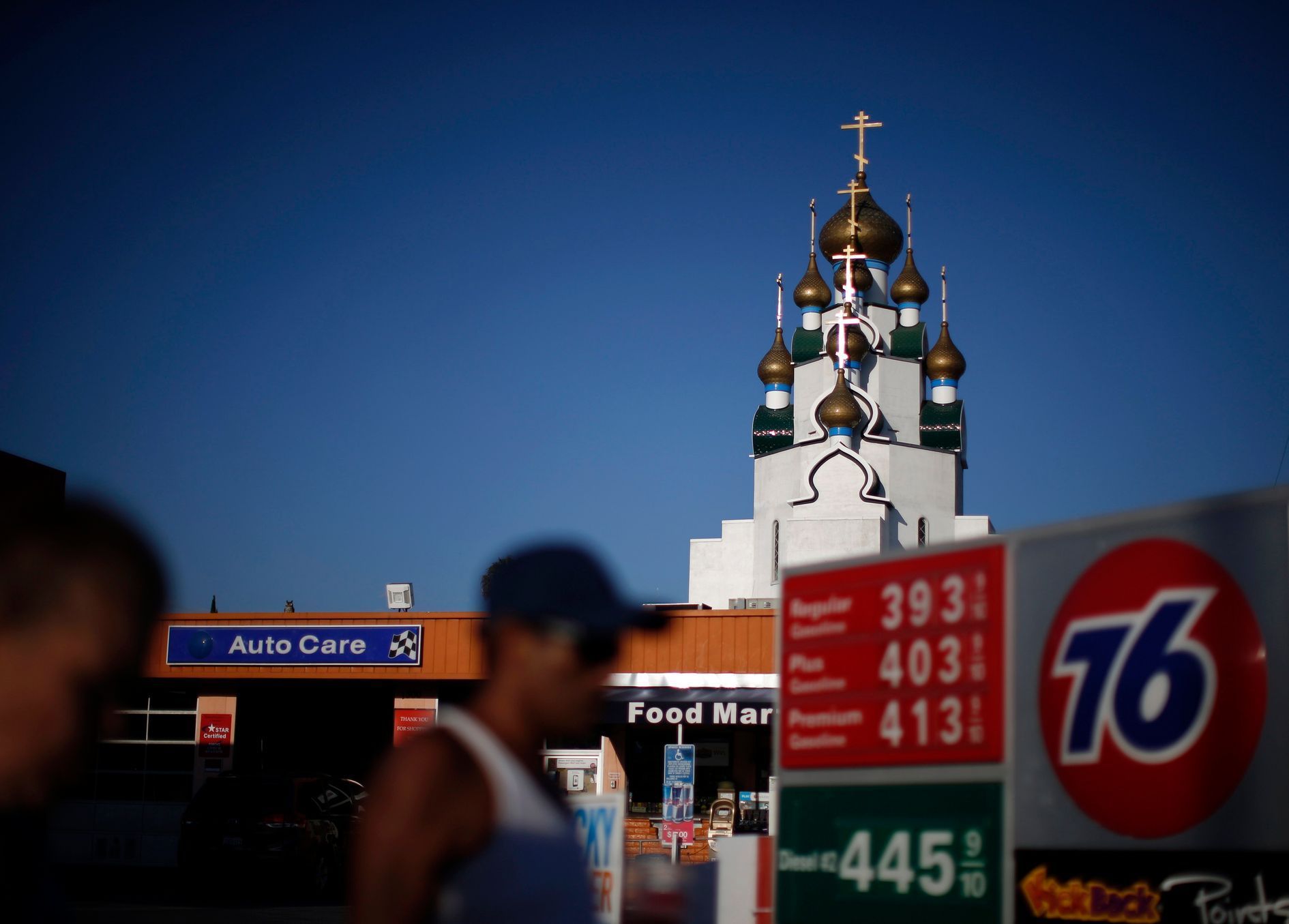 People walk past a gas station as a Russian Orthodox Church is seen in the distance in Hollywood, California