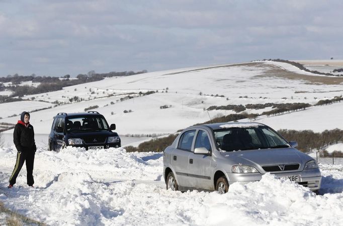 A man waits by a car stuck in snow on the South Downs near Brighton in southern England March 12, 2013. Drivers were left stranded on Tuesday following a second day of heavy snowfall in southern England. REUTERS/Luke MacGregor (BRITAIN - Tags: ENVIRONMENT SOCIETY) Published: Bře. 12, 2013, 4:58 odp.