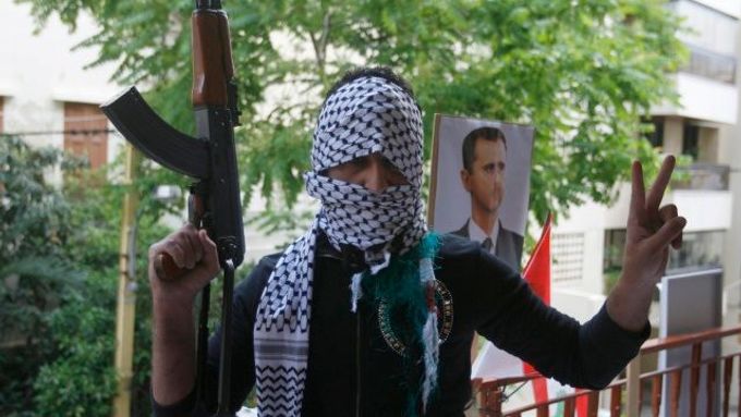 Bojovník Hizballáhu pózuje před portrétem Bašára Asada.