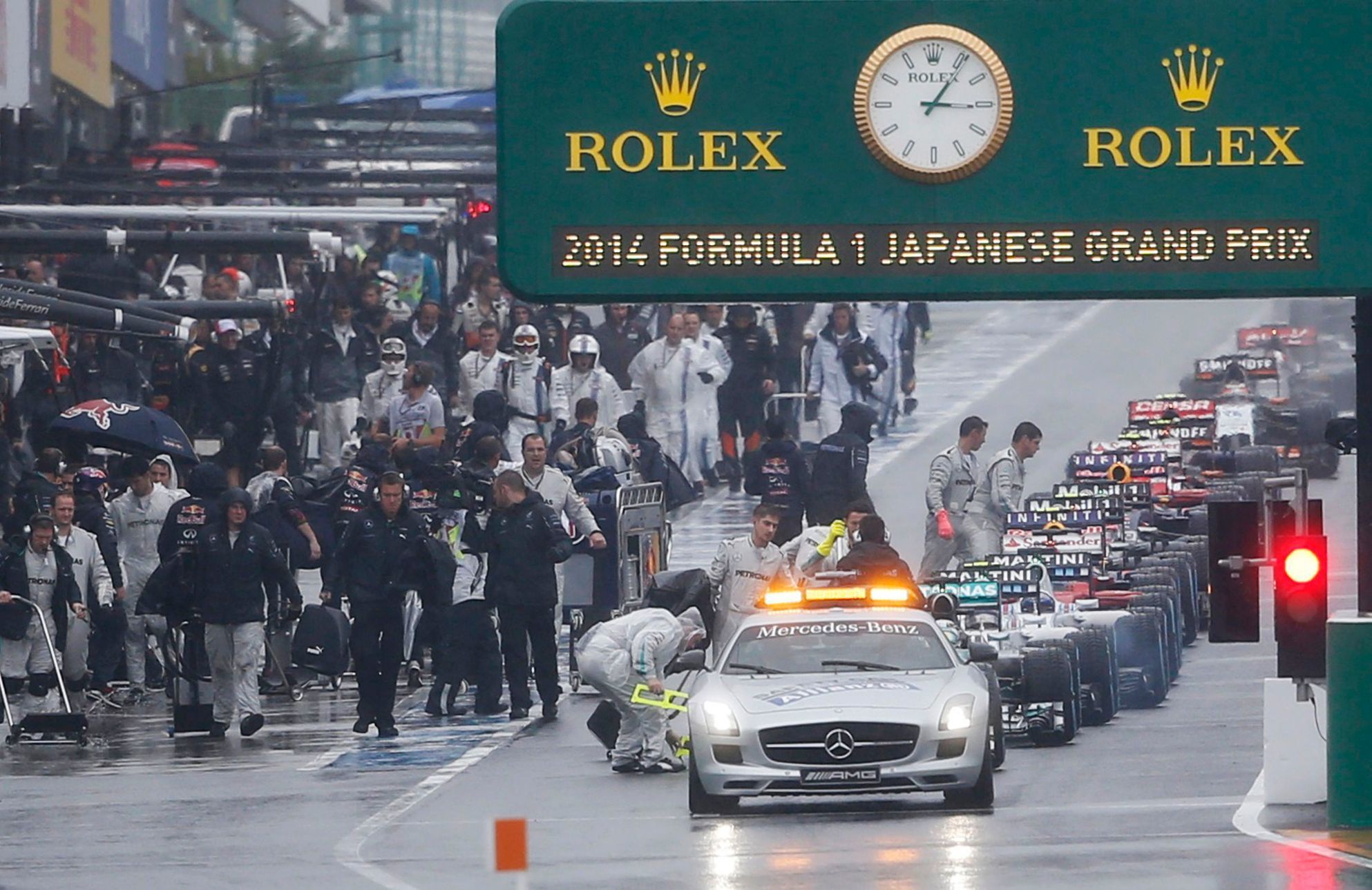 Cars line up behind the safety car in the pit lane as the race is suspended due to rain conditions during the Japanese F1 Grand Prix at the Suzuka Circuit