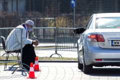 Polský kněz zpovídá lidi na parkovišti před kostelem. Zájemci k němu jezdí autem